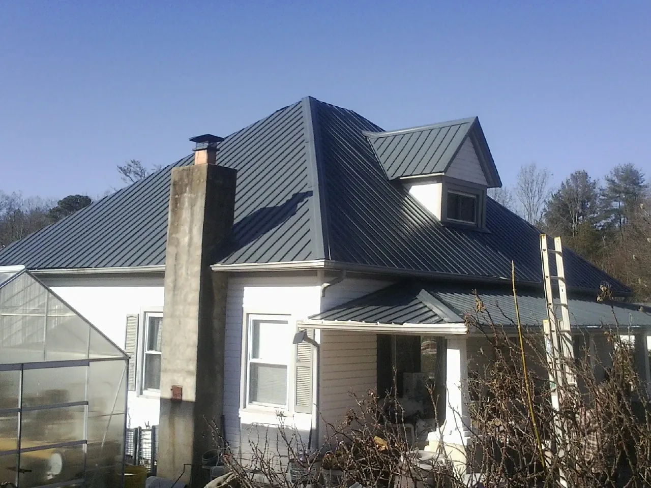 Dark blue standing seam metal roof on a white farmhouse with dormer — Slate & Tile Roof Repair by Roofing Brothers in North Yarmouth