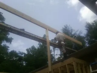 Carpenter setting a ridge beam over a new addition frame — Ice Dam Removal by Roofing Brothers in North Yarmouth