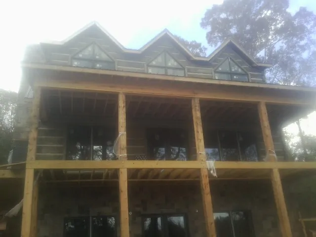Dormers and porch framing on a large log home under construction — Roof Coating work by our crew in North Yarmouth