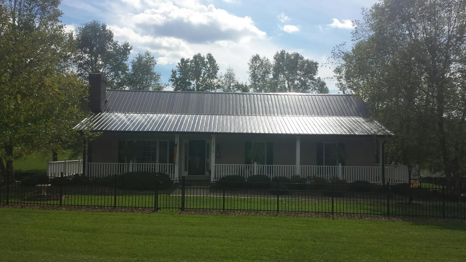 Gray metal roof on a brick ranch with a full width front porch — Gutter Guard Installation work by our crew in North Yarmouth