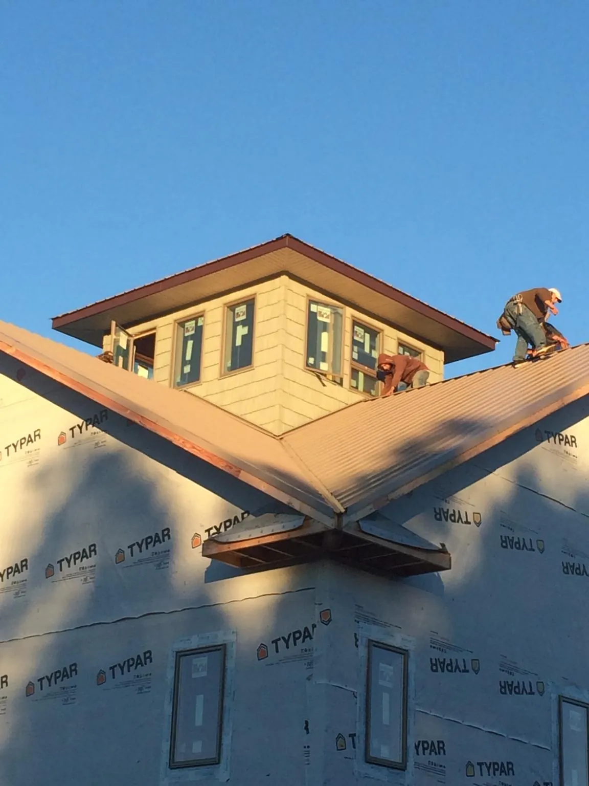 Roofers working around a rooftop cupola on a new metal roof at sunset — Roof Waterproofing in North Yarmouth by Roofing Brothers